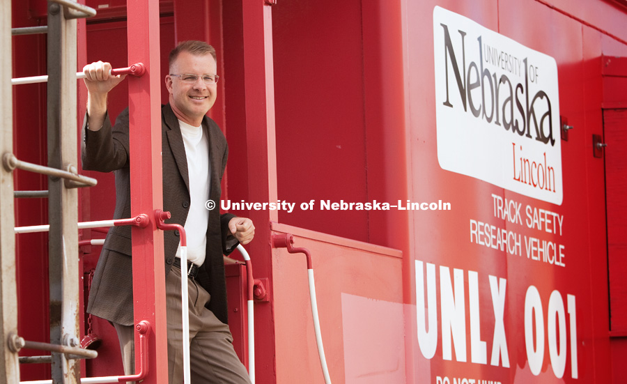 Dr. Shane Farritor poses on a caboose custom painted and donated to the University of Nebraska–Lincoln. The Husker red caboose was used to house the measuring equipment and generators used on the first-generation test car. The current test car is a self-contained hopper car. Track modulus is one of several indicators for the quality and performance of railroad track. It is the ratio of vertical rail deflection and the contact pressure between the rail base and track foundation.Photo by Craig Chandler / University Communications
