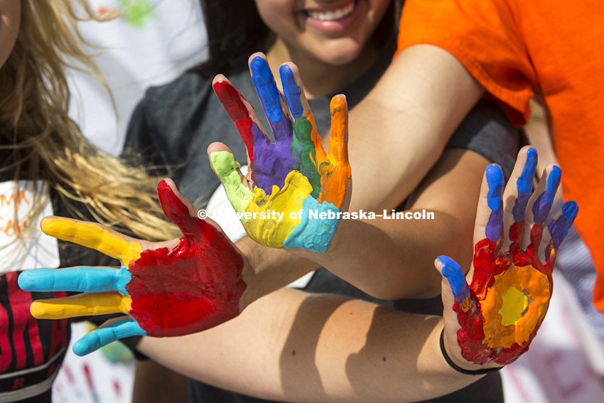 Painted hands are ready to be stamped onto a banner at one station. Learning Community Welcome Event.  Groups went through several stations including an inflatable obstacle course and one where students put painted hand-prints on a giant banner to be displayed in Abel Sandoz Residence Hall. Photo by Craig Chandler / University Communications