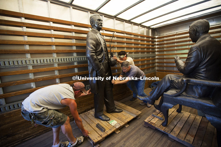 J. Sterling Morton slides past Clifford Hardin with the help of Landscape Services and sculptor Matthew Placzek, center in gray shirt, as the statues await transport from the back of a truck to their East Campus locations Monday morning. Statues of the four US State Senators that were appointed Secretary of Agriculture who were from Nebraska; J. Sterling Morton, Clifford Hardin, Clayton Yeutter, and Mike Johanns are being erected on East Campus this week. They will be dedicated in a ceremony Saturday, September 20, 2014. Photo by Craig Chandler / University Communications