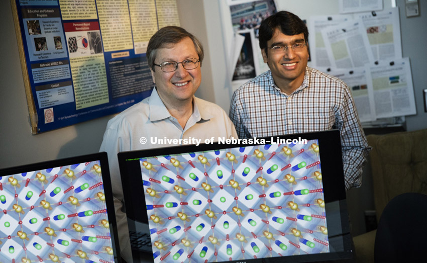 Evgeny Tsymbal and Tula R. Paudel pose in a Jorgensen Hall office. On screen is a schematic representation of an atomic structure of the system they studied. It is a top view of the surface, so that in depth they see atomic layers. Arrows indicate magnetism which has been experimentally observed by colleagues and theoretically predicted by them. July 29, 2015. Photo by Craig Chandler/University Communications