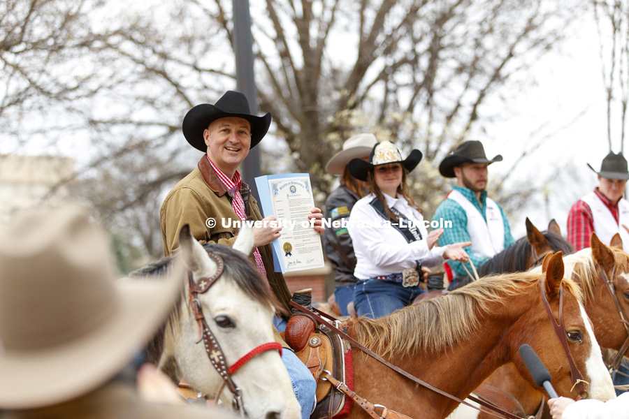 Governor Pete Ricketts holds up the proclamation announcing this week as "Rodeo Week" in honor of the UNL Rodeo this weekend. The Governor rode with the University of Nebraska-Lincoln rodeo team on the streets around the Governor's Mansion. April 10, 2017