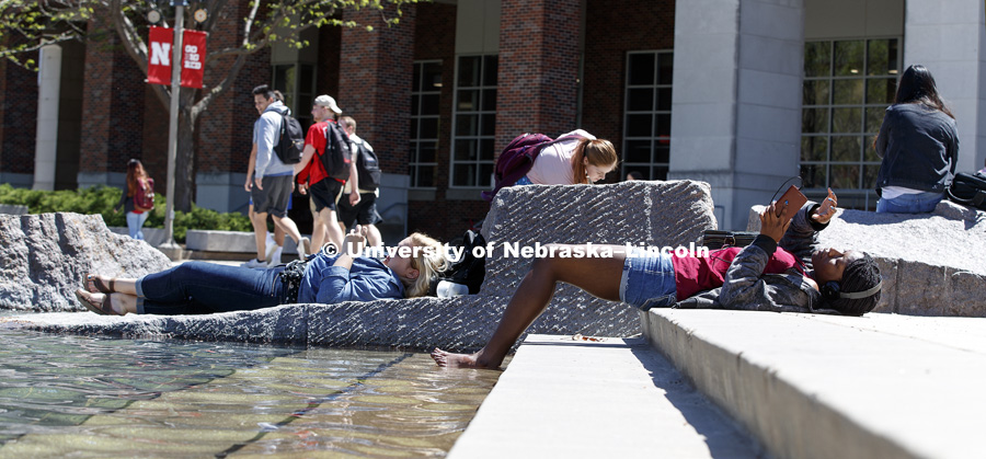 Nadria Beale, right, and Devon Gottsch enjoy Thursday's sunshine. Students hanging out around the fountain on city campus. April 20, 2017. Photo by Craig Chandler / University Communication.