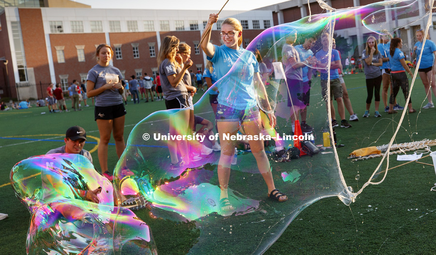 Ashley Suik and her teammate Emily Rodriguez makes bubbles at one of the group stations during the All-Learning Community Welcome Event on Mabel Lee field. August 17, 2017. Photo by Craig Chandler / University Communication.