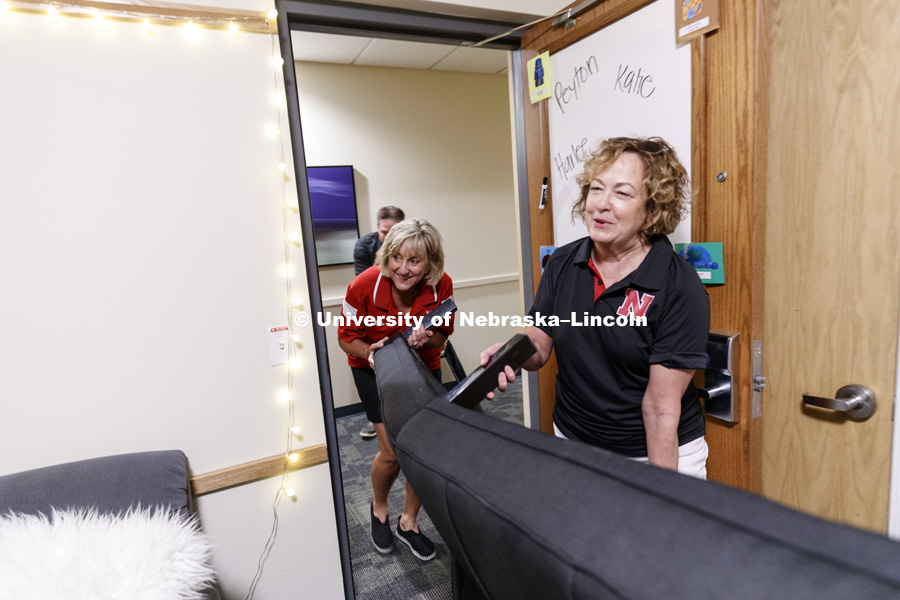 Donde Plowman, Executive Vice Chancellor and Chief Academic Officer, and Laurie Bellows, Vice Chancellor for Student Affairs, help carry a futon into a room on city campus' Knoll Residence Hall. August 17, 2017. Photo by Craig Chandler / University