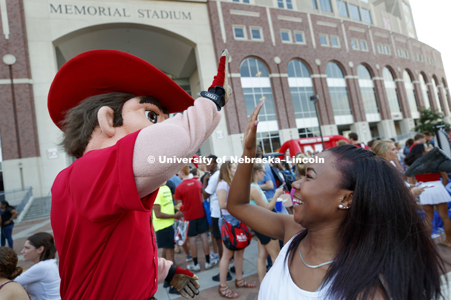 Erin Hunter, a sophomore in broadcast journalism, high fives Herbie Husker at the Street Festival between the College of Business and Memorial Stadium as part of the Big Red Welcome. August 20, 2017. Photo by Craig Chandler / University Communication.