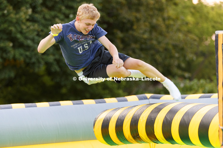 Cameron Hosler leaps over a revolving column as he tries to beat the spinning Meltdown inflatable. Back to School Bash on the Nebraska Union Plaza and Green Space sponsored by Campus NightLife. Students enjoyed a headphone disco party, inflatable games,