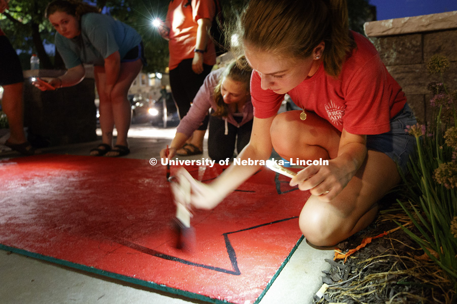 Tori Rojas of Alpha Delta Pi paints a sign by the light of her cell phone Thursday evening. Homecoming lawn displays. September 21, 2017. Photo by Craig Chandler / University Communication.