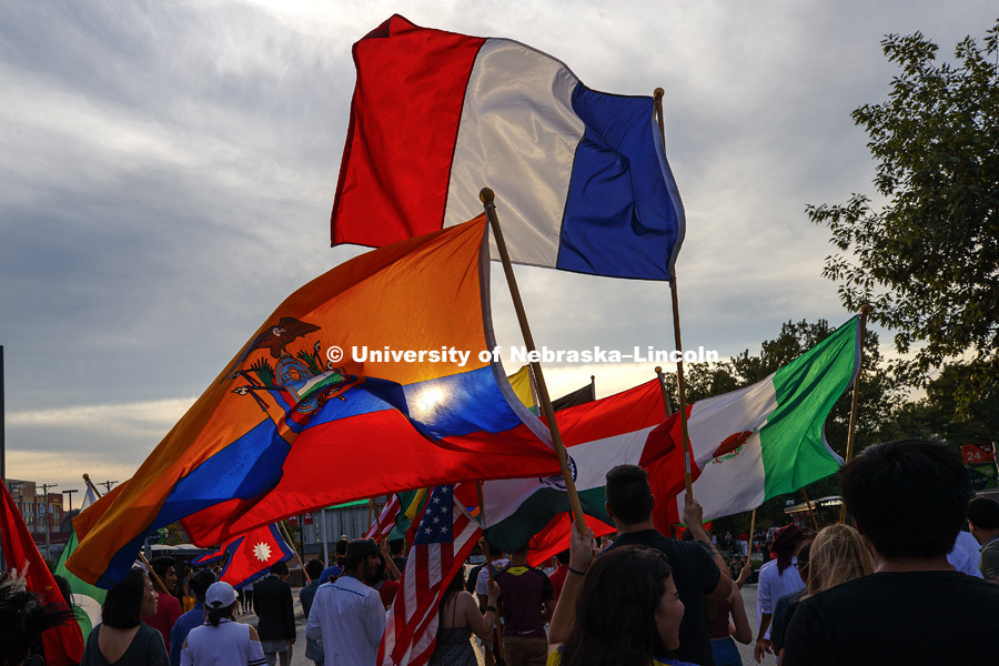 Flags carried by international students in the parade are silhouetted by the setting sun. Homecoming parade, pep rally and court jester competition. September 22, 2017. Photo by Craig Chandler / University Communication.