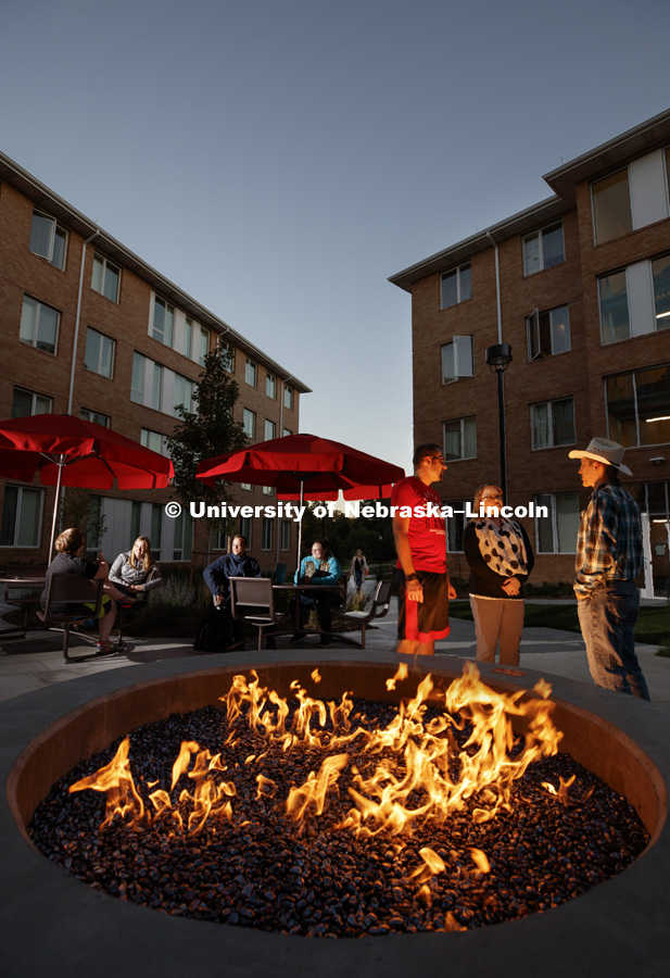 Students warm themselves by the fire pit outside of Massengale Residence Hall on East Campus, October 11, 2017. Photo by Craig Chandler / University Communication.