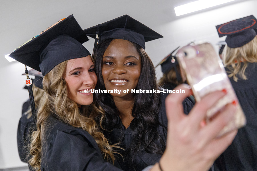 Emily Marie Johnson and Olga Mwenentanda take a selfie while the two CEHS students await graduation. Undergraduate Commencement at Pinnacle Bank Arena. December 16, 2017. Photo by Craig Chandler / University Communication.