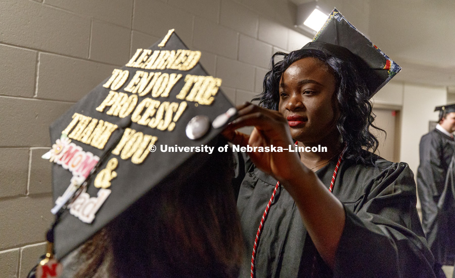 Claire Ngamelue adjusts the mortar board on her friend, Gazmine Mason before the Undergraduate Commencement at Pinnacle Bank Arena. December 16, 2017. Photo by Craig Chandler / University Communication.