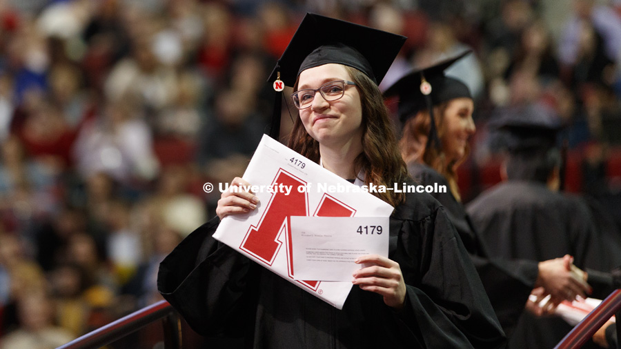 Elizabeth Thorne smiles as she shows family and friends her College of Business diploma. Undergraduate Commencement at Pinnacle Bank Arena. December 16, 2017. Photo by Craig Chandler / University Communication.