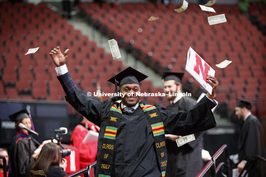 Joshua Kalu shows off his CEHS diploma after tossing a hand full of dollar bills into the air as he walked off the stage. Undergraduate Commencement at Pinnacle Bank Arena.  December 16, 2017. Photo by Craig Chandler / University Communication.
