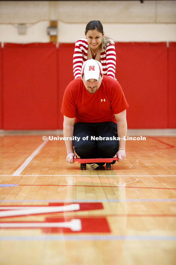 Chris Berggren is pushed by Ashley Durst as they work with scooters. Masters students in TEAC 893 Seminar Workshop in Health & Physical Education apply learning principals to physical education games in Mabel Lee hall gymnasium.  January 12, 2018. Photo