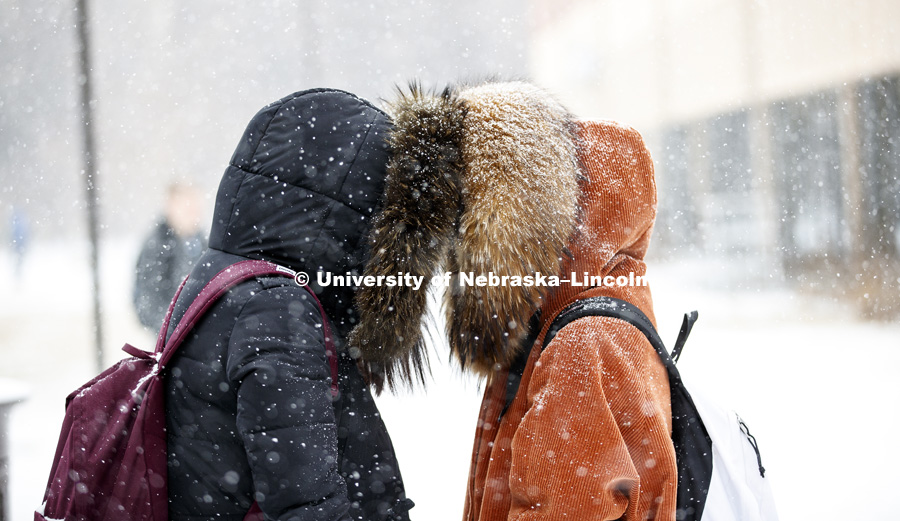 Fangyi Zhai and Miao Hong use the hoods of their coats to make it easier to talk in between classes Monday. Snow on campus. February 5, 2018. Photo by Craig Chandler / University Communication.