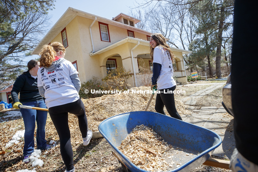 Haley Stellingwerf, Lincoln, and her Newman Center team tackle a large pile of mulch along 37th Street. Big Event. April 7,  2018. Photo by Craig Chandler / University Communication.