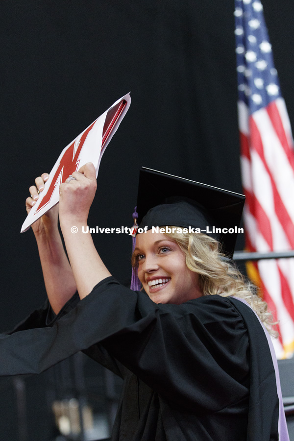 Hannah Janda holds up her masters degree in community and regional planning for her family and friends to see. Graduate Commencement at Pinnacle Bank Arena. May 4, 2018. Photo by Craig Chandler / University Communication.