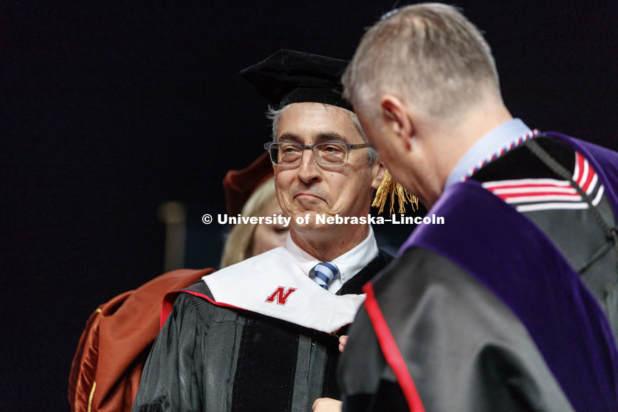 Alexander Payne is hooded as part of his honorary doctorate degree.  Behind him is Executive Vice Chancellor Donde Plowman and in front is University of Nebraska Regent Tim Claire. Undergraduate Commencement at Pinnacle Bank Arena. May 5, 2018. Photo by