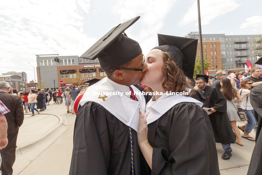 Chemical Engineering graduates Julian Davis and Mary Rethwisch share a kiss after commencement. Undergraduate Commencement at Pinnacle Bank Arena. May 5, 2018. Photo by Craig Chandler / University Communication