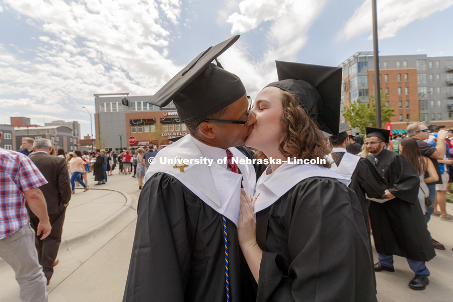 Chemical Engineering graduates Julian Davis and Mary Rethwisch share a kiss after commencement. Undergraduate Commencement at Pinnacle Bank Arena. May 5, 2018. Photo by Craig Chandler / University Communication