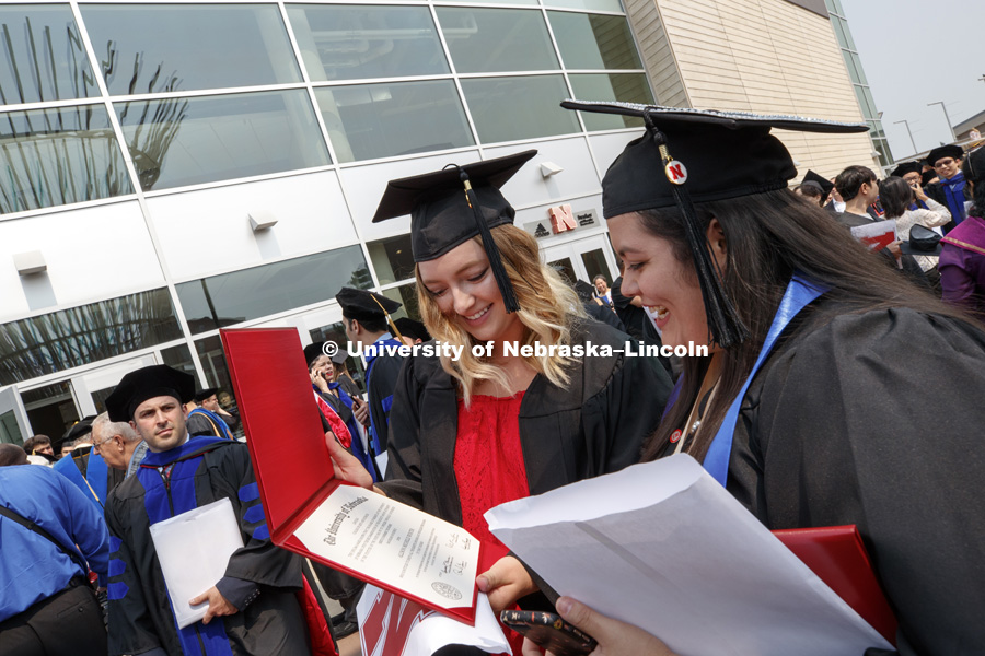 Allison Winter and Ariel Medrano admire each others diplomas following Summer Commencement at Pinnacle Bank Arena. August 11, 2018. Photo by Craig Chandler / University Communication.