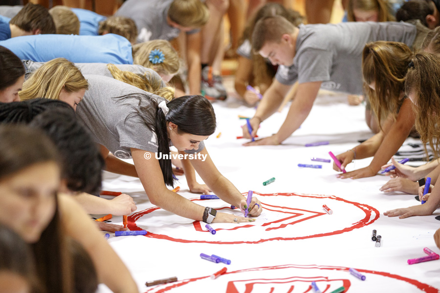 Students trace their hand and sign their name to a huge banner at the Learning Community Welcome Event in the rec center. The banner will hang in Abel Sandoz Residence Center for the school year. August 17, 2018. Photo by Craig Chandler / University
