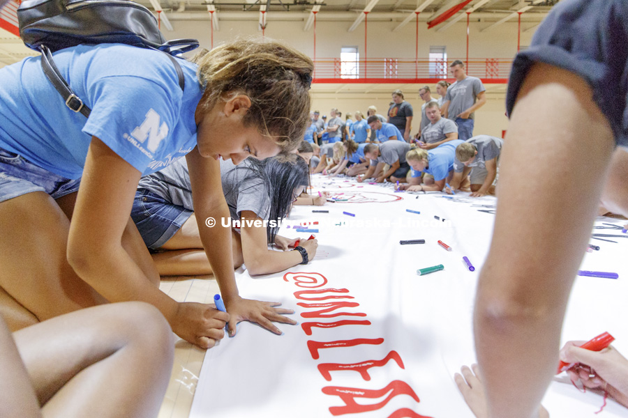 Students trace their hand and sign their name to a huge banner at the Learning Community Welcome Event in the rec center. The banner will hang in Abel Sandoz Residence Center for the school year. August 17, 2018. Photo by Craig Chandler / University
