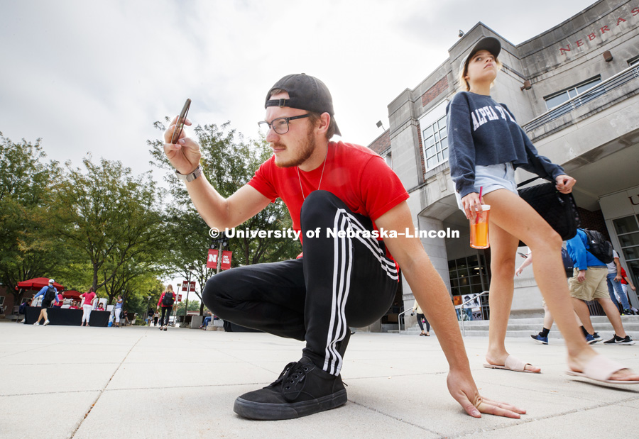 Mitchell Francis, a sophomore from Omaha, gets the angle for a photo of the Grit and Glory words in front of the fountain. In Our Grit, Our Glory brand reveal party on city campus at the Nebraska Union. August 30, 2018. Photo by Craig Chandler / University Communication.