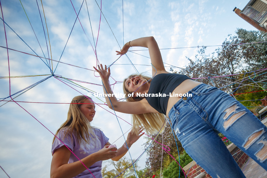 Elizabeth Nesland tries to untangle herself as she, Taylor Yarnell and other Alpha Omicron Pi freshman unravel a string maze to find sorority t-shirts at the end of their individual string. Homecoming 2018 decorating yard displays. September 27, 2018. Photo by Craig Chandler / University Communication.