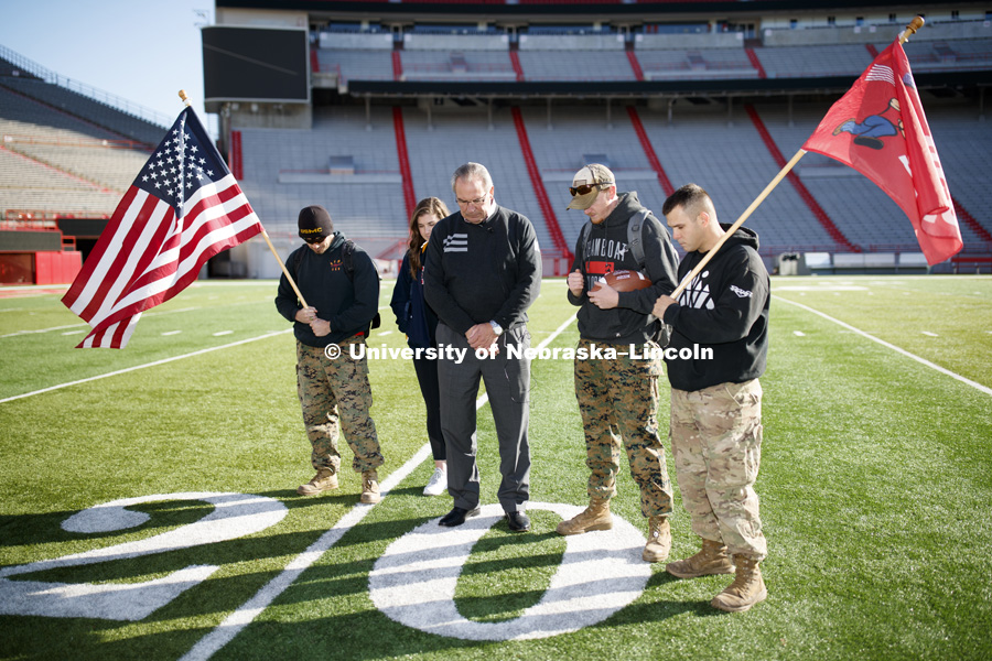 Jerod Post, '13 and a Marine veteran, undergraduate Natalie Kraft, a Navy veteran, Athletic Director Bill Moos, undergraduate and Marine veteran Jake Post and undergraduate and Army veteran Jared Collins observe a moment of silence prior to the starting point of the Ruck March. Beginning of veterans Ruck March, which uses Nebraska and Iowa veterans to carry the game ball from Lincoln to Iowa City. November 14, 2018. Photo by Craig Chandler / University Communication.