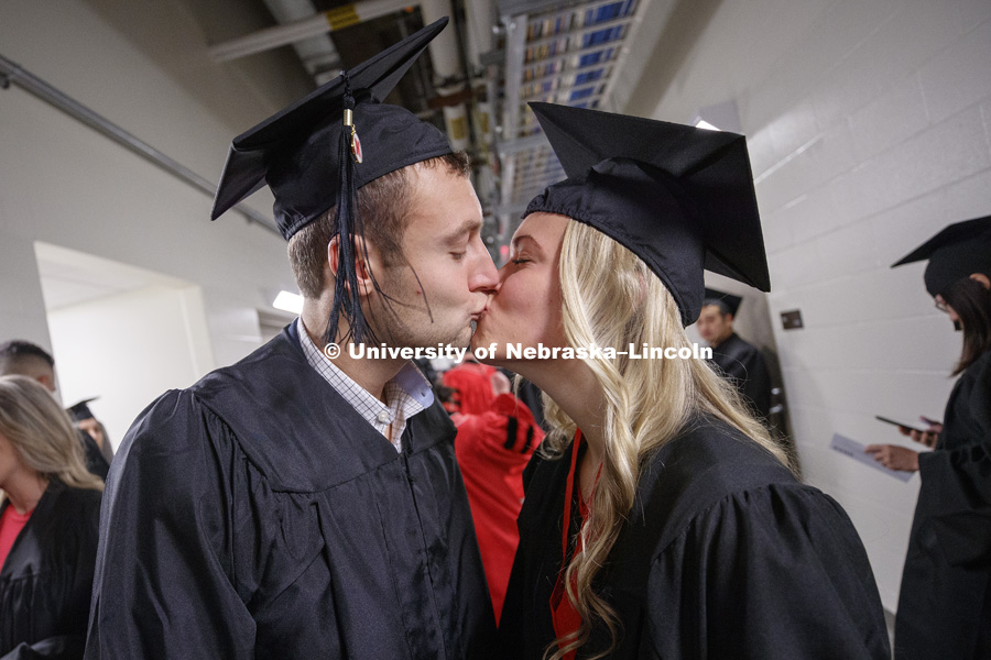 Thomas Kayton and Lynsey Coufal share a kiss before commencement.  The two graduates will marry in May. Undergraduate Commencement in Pinnacle Bank Arena. December 15, 2018. Photo by Craig Chandler / University Communication.