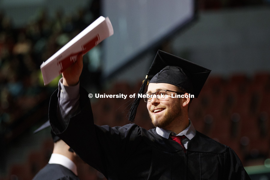 Nolan Graham shows off his diploma for family and friends at the Undergraduate Commencement in Pinnacle Bank Arena. December 15, 2018. Photo by Craig Chandler / University Communication.