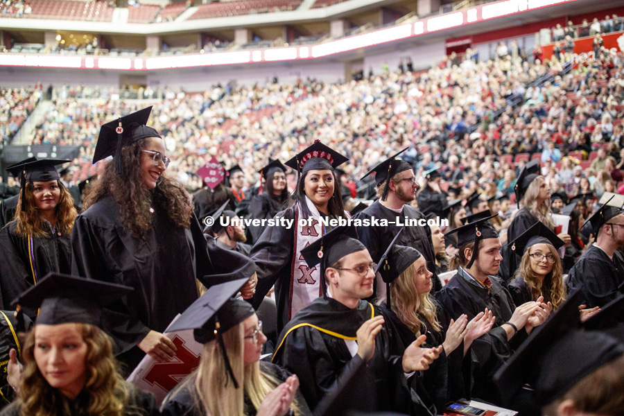 Mariel Limon and Yajaira Lopez-Villa clasp hands as they stand when the Chancellor asked all First Generation students to be recognized at the Undergraduate Commencement in Pinnacle Bank Arena. December 15, 2018. Photo by Craig Chandler / University Communication.