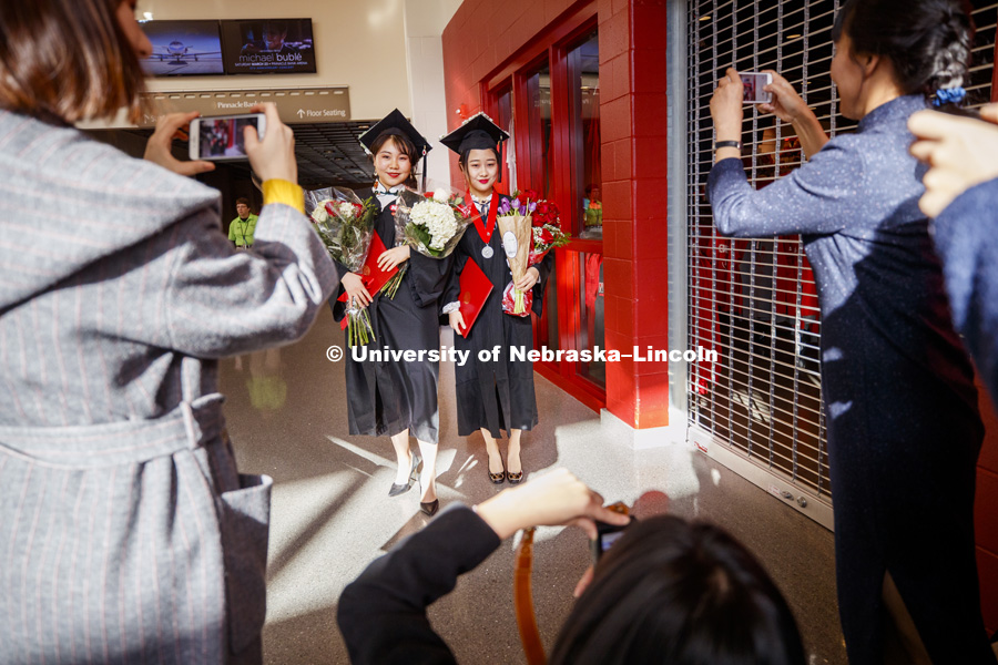 New graduates pose with arm loads of flowers after the Undergraduate Commencement in Pinnacle Bank Arena. December 15, 2018. Photo by Craig Chandler / University Communication.