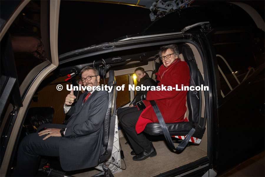 Chancellor Ronnie Green puts on a headset as he, his wife, Jane, and son, Nathan, prepare for a flight by Husker Helicopter's Kim Wolfe at left. Glow Big Red bathes the campuses with red lights as part of N150's Charter Week celebration. February 14, 2019. Photo by Craig Chandler / University Communication.
