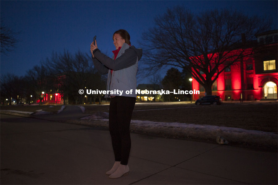 Academic Advisor Molly Brandt takes a picture with her phone during Glow Big Red. Glow Big Red bathes the campuses with red lights as part of N150's Charter Week celebration. February 14, 2019. Photo by James Wooldridge for University Communication.