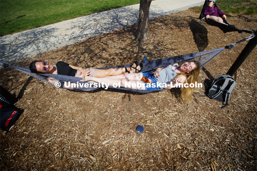 Sammy Cope, freshman from Omaha, plays an air guitar backup to her play list as she and Calli Mah, freshman from Mitchell, South Dakota, hang out in the hammocks by the Broyhill fountain. Spring Day on City Campus. April 9 2019. Photo by Craig Chandler / University Communication.