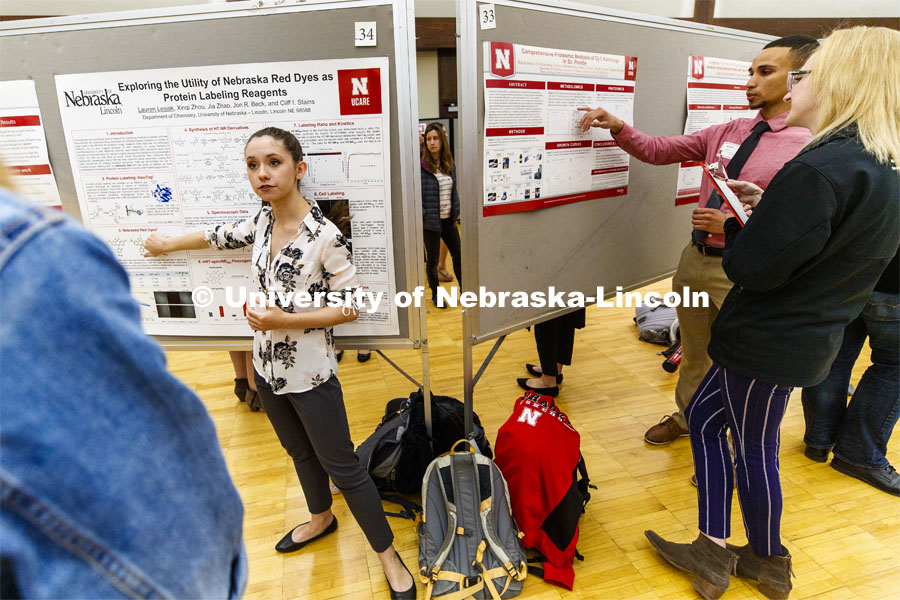 The Union ballroom becomes a hundred conversations at once including Lauren Lesiak, left, presenting her research while to the right is Kaleb Jones presenting his. Undergraduate Spring Research Fair in the Union ballrooms. April 15, 2019. Photo by Craig Chandler / University Communication.
