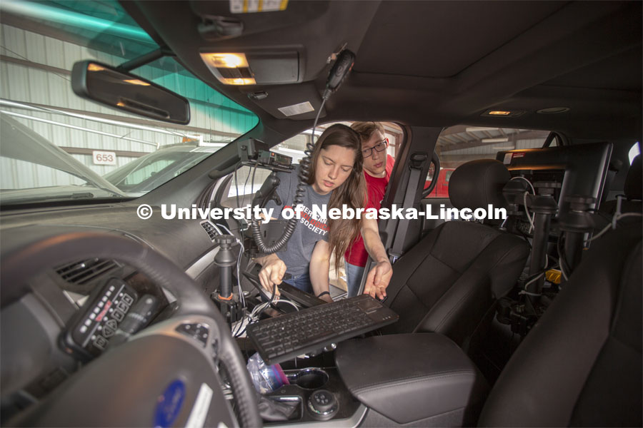 Nebraska students (from left) Maddy Diedrichsen and Brennan Darrah work on installing a new monitor and keyboard into the passenger seat of a mesonet (storm chase) vehicle during prep work for the TORUS project. April 26, 2019. Photo by Troy Fedderson / University Communication