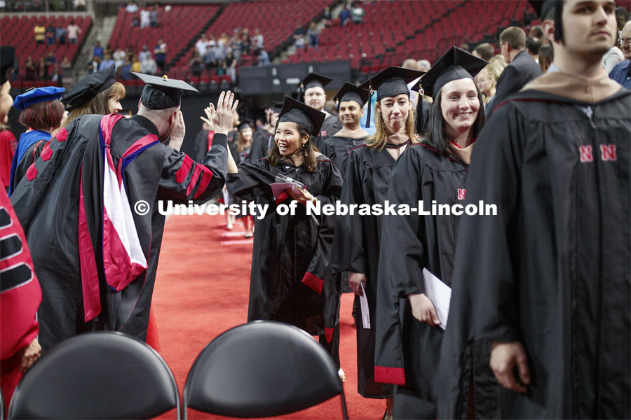 Mi Huynh exchanges high fives with faculty members who lined the processional. 2019 Spring Graduate Commencement in Pinnacle Bank Arena. May 3, 2019. Photo by Craig Chandler / University Communication