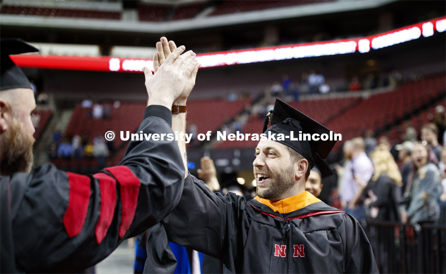 Ross Barron exchanges high fives with faculty members who lined the processional. 2019 Spring Graduate Commencement in Pinnacle Bank Arena. May 3, 2019. Photo by Craig Chandler / University Communication