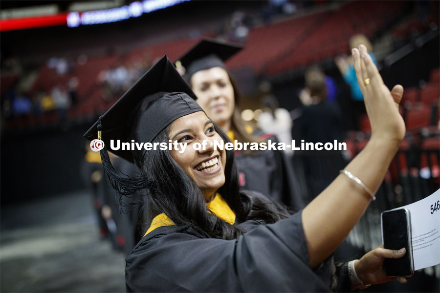 Kiran Sharma waves to family and friends during the processional. 2019 Spring Graduate Commencement in Pinnacle Bank Arena. May 3, 2019. Photo by Craig Chandler / University Communication