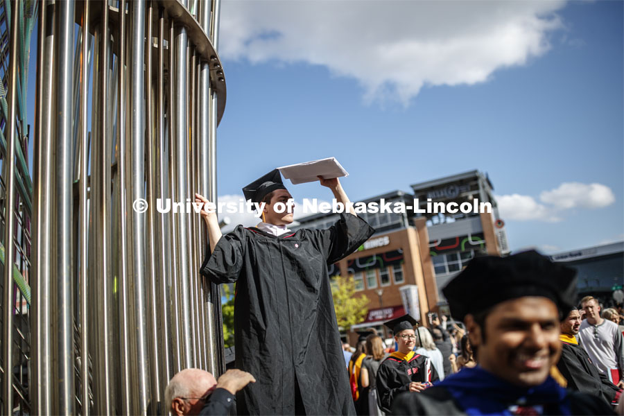 Cole Juckette uses the sculpture to gain a little height while searching for his family and friends after the 2019 Spring Graduate Commencement in Pinnacle Bank Arena. May 3, 2019. Photo by Craig Chandler / University Communication
