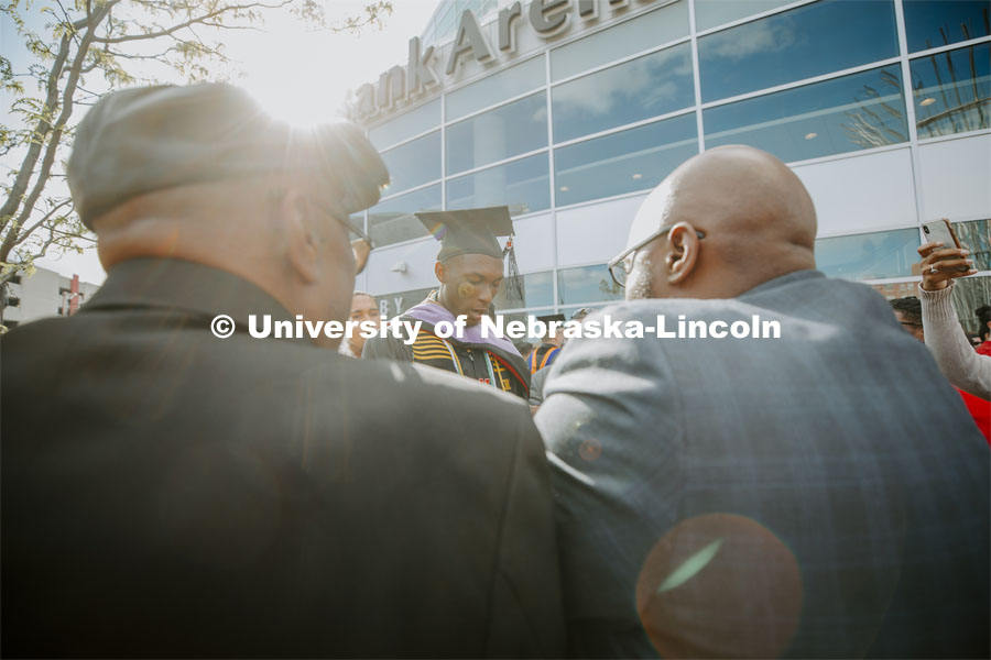 Friends, family and fellow Alpha Phi Alpha fraternity brothers form a circle around Davielle Phillips outside the arena following commencement. Phillips earned dual degrees of MBA and Master of Architecture. 2019 Spring Graduate Commencement in Pinnacle Bank Arena. May 3, 2019. Photo by Craig Chandler / University Communication