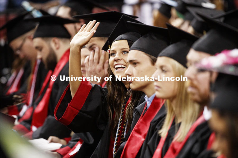 A young woman waves to her family. Undergraduate commencement at Pinnacle Bank Arena, May 4, 2019. Photo by Craig Chandler / University Communication.