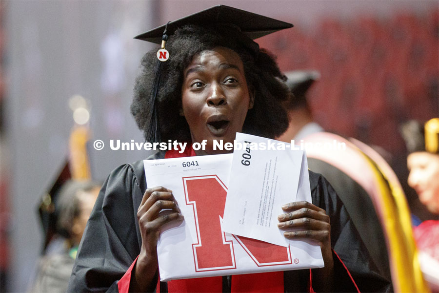 Aguel Lual gestures to family and friends as she walks off stage with her Fine and Performing Arts degree. Undergraduate commencement at Pinnacle Bank Arena, May 4, 2019. Photo by Craig Chandler / University Communication.