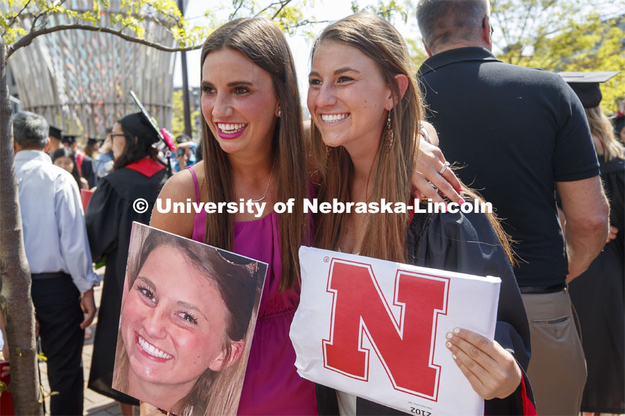 Hailey Lehms poses with her sister, Lindsey, after the commencement. Her family held up large photos of her to make it easier to meet up. Undergraduate commencement at Pinnacle Bank Arena, May 4, 2019. Photo by Craig Chandler / University Communication.