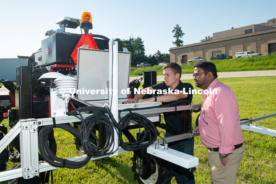 Grad student Josh Murman is with Santosh Pitla, associate professor of advanced machinery systems in the Department of Biological Systems Engineering at the University of Nebraska–Lincoln. Pitla is currently developing an autonomous tractor using ground robotics. Pitla and his team are testing their driverless tractor on the tractor testing field on East Campus. The autonomous tractors are named Flexible Structured Robotic Vehicle (FlexRo), the tractor is currently used for plant phenotyping, which is measuring the physical characteristics of the plant. According to Pitla, cameras are added to the machine to collect images that characterize plant conditions. Photo for the 2019 publication of the Strategic Discussions for Nebraska magazine. June 10, 2019, Photo by Gregory Nathan / University Communication. 