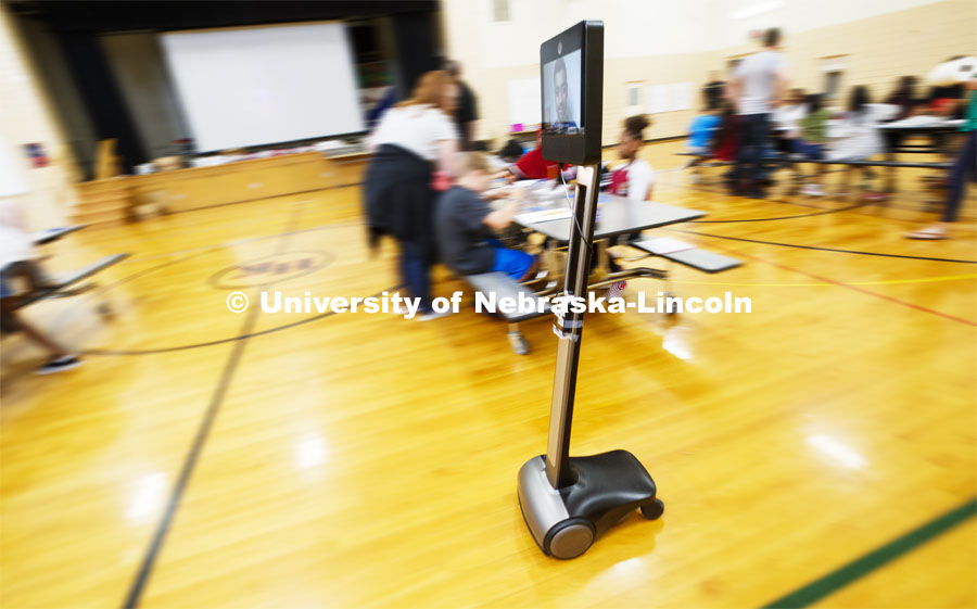 Soham Patel, a UNL computer science major, uses Beam technology to wheel around the class being held in the gym. Patel helps teach the class remotely from Lincoln. Patel is able to not only video conference with the class but the screen is mounted on a robotic platform so he can wheel around the gym to help groups of students.  Elementary-age students in Omaha's Kennedy Elementary learned about nano technology and water Wednesday afternoon. STEMentors is helping put on summer camps with Imagine Science. June 19, 2019. Photo by Craig Chandler / University Communication.