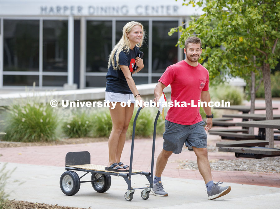 Gabbi Circo catches a ride on a cart piloted by Nate Miller as they begin to move in her belongings. Residence Hall Move-in. August 18, 2019. Photo by Craig Chandler / University Communication.